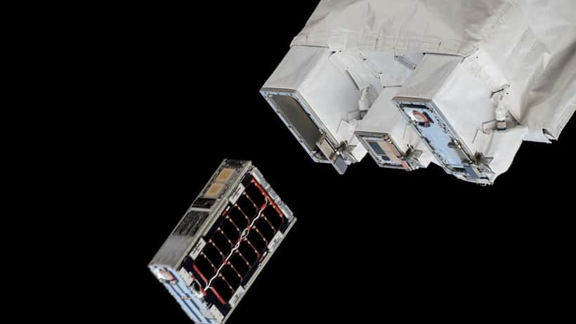 A CubeSat satellite being ejected into low Earth orbit from the ISS deployer, Earth curvature visible below