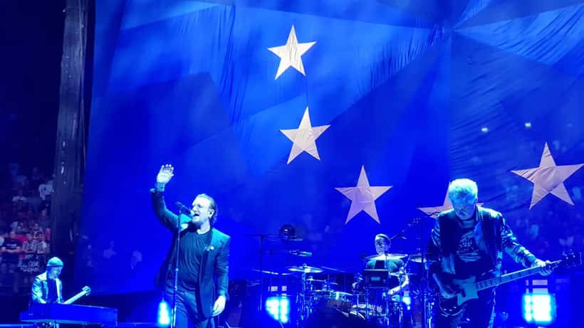 U2 em concerto ao vivo no palco com luzes de espetáculo e multidão de fãs