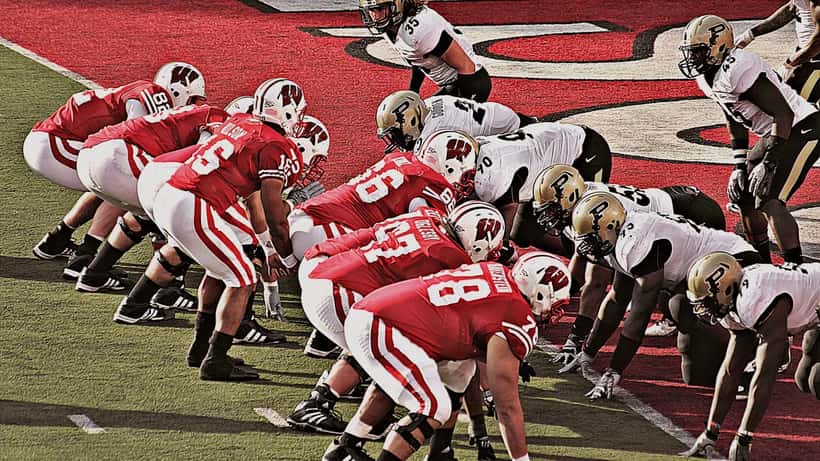 Russell Wilson quarterbacking during a college game at Purdue, dropping back to pass in a football uniform
