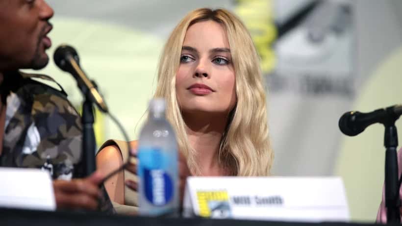 Margot Robbie at public event smiling in formal attire