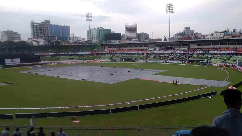 Cricket pitch covered during rain delay at a stadium, match play abandoned