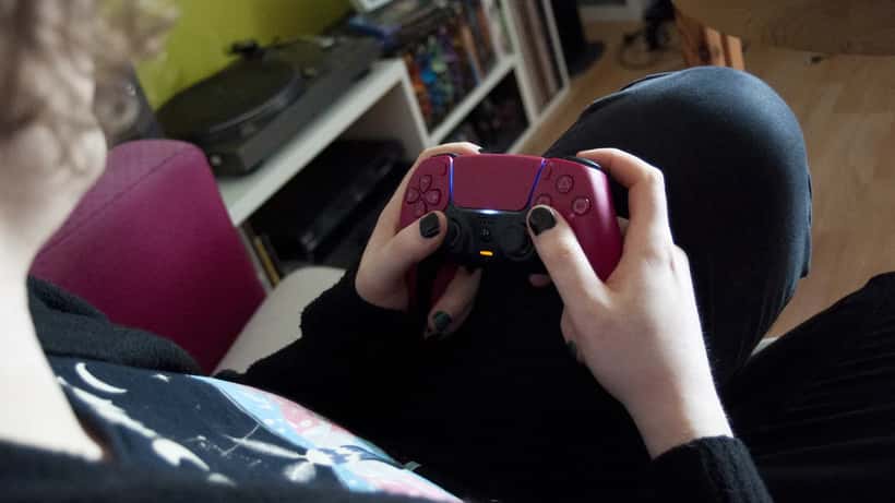 Person holder PS5-kontroller og spiller digitalt spill