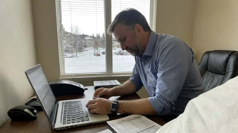 Canadian man reviewing sports betting app and legal documents at home desk