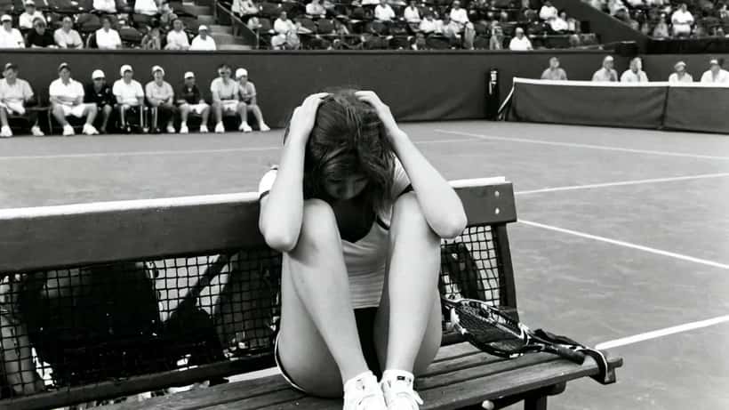 Jeune joueuse de tennis assise sur le banc de côté en état de détresse après un match