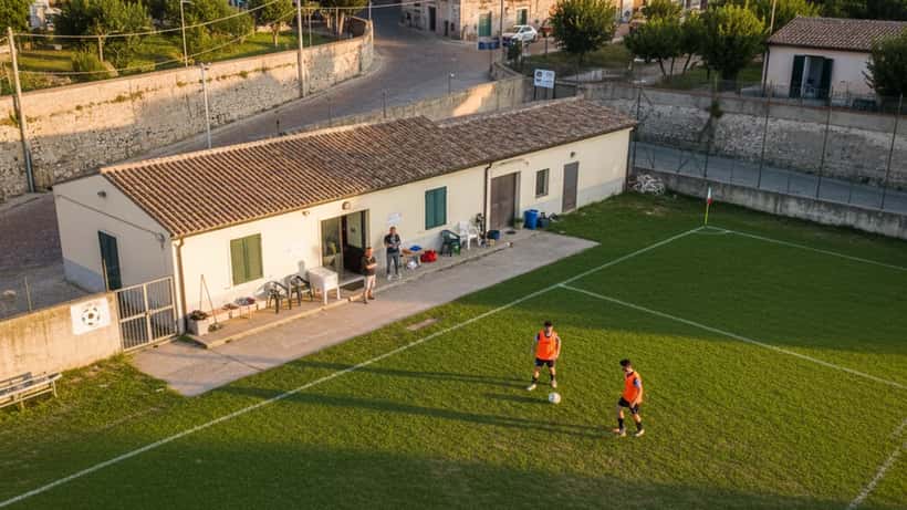 Campo di calcio amatoriale italiano al tramonto con due giocatori in allenamento