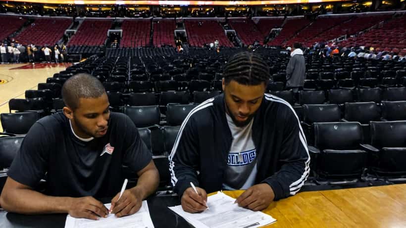 Young basketball player reviewing contract documents with a financial advisor at an NBA arena