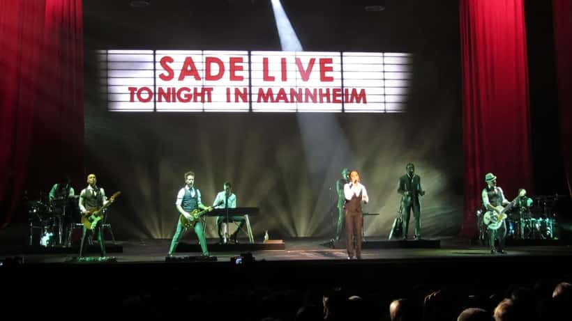Sade Adu performing on stage with her band during a live concert