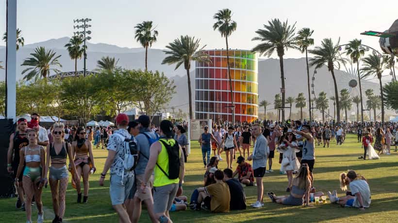 Multidão animada no Coachella Music Festival com luzes e palco ao fundo