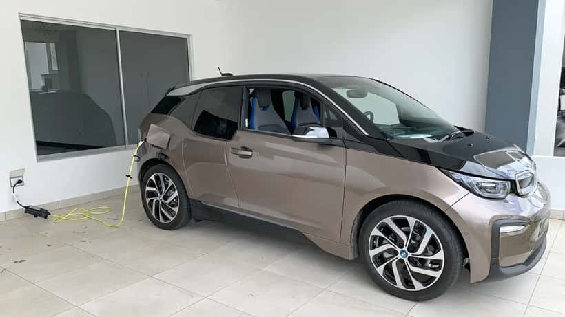 BMW i3 electric vehicle plugged into a home charging station