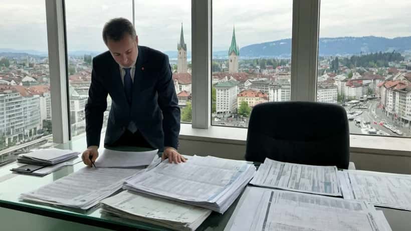 Conseiller patrimonial suisse examinant des documents fiscaux liés à un gain EuroMillions dans un bureau à Zurich