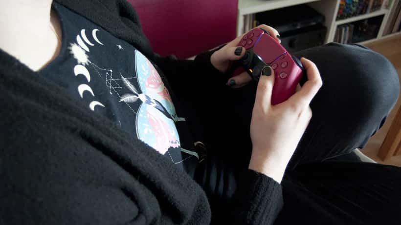 Henkilö pelaa PlayStation 5:tä PS5-ohjaimella vaaleassa ympäristössä