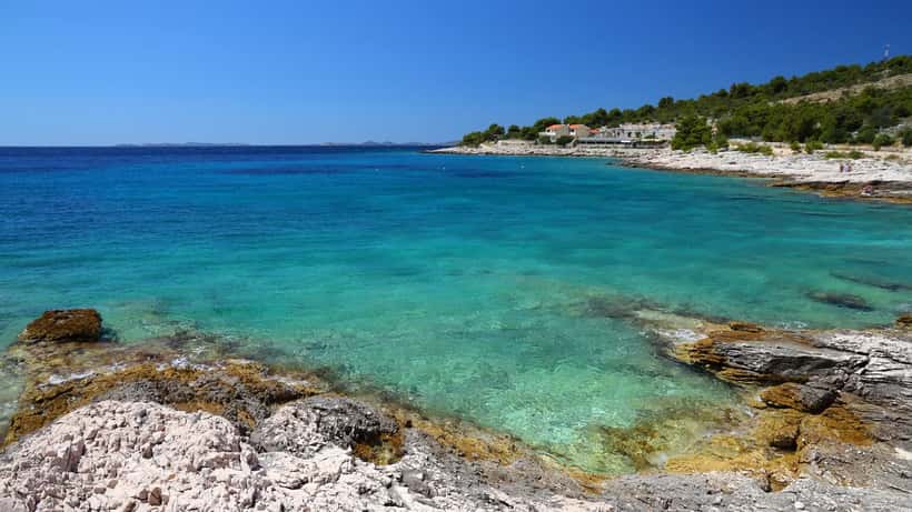 Kroatische Adria-Küste mit türkisfarbenem Meer und Fischerboot in Dalmatien