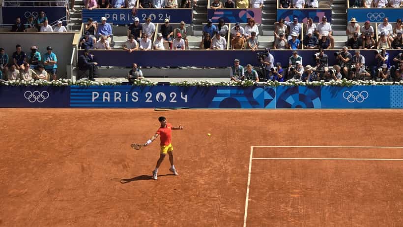 Carlos Alcaraz playing at the 2024 Paris Olympics against Novak Djokovic, mid-match action shot