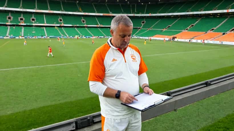 Voetbalcoach op de zijlijn van een Eredivisie-stadion met clipboard