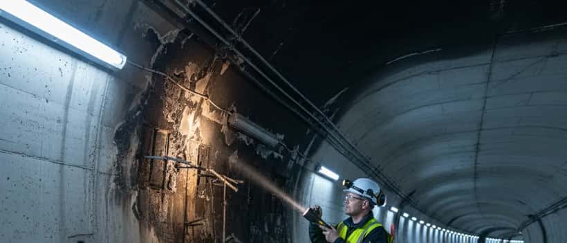 Norsk bygningsinspektør med sikkerhetsvest undersøker brannskader i tunnel