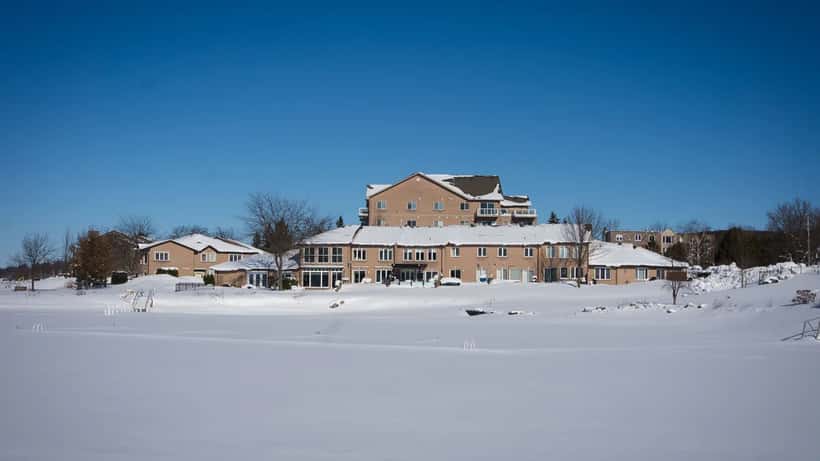 Buildings covered in snow and ice beside a frozen lake in Canada during winter 2026