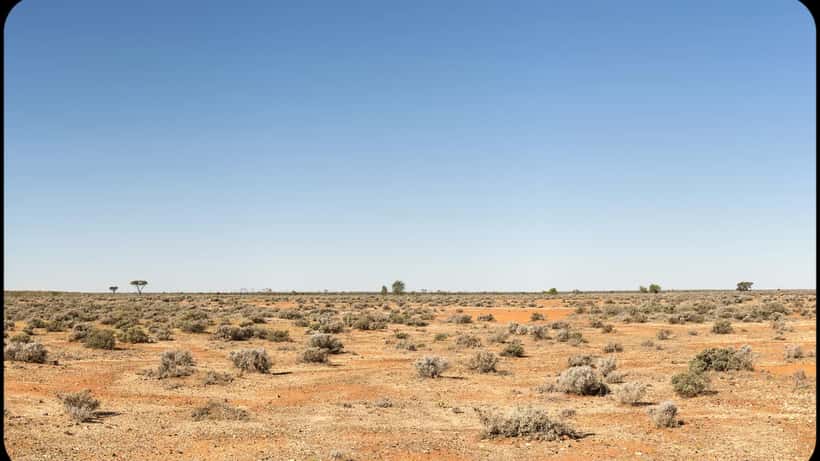 Empty red-dirt highway stretching through the Northern Territory outback scrub at dusk