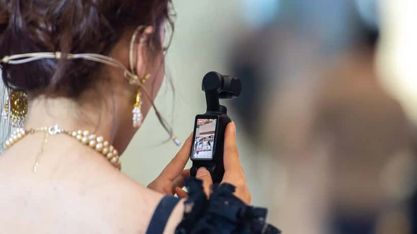 Person recording video using a DJI Osmo Pocket 3 gimbal camera at an event