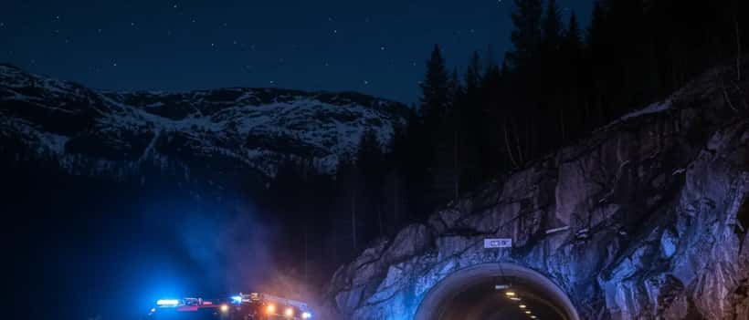 Nødetater jobber utenfor en norsk bergtunnel om natten etter bussbrann på E6 i Sørfold
