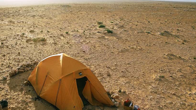 Paysage désertique du Sahara occidental avec campement bédouin sous un ciel bleu