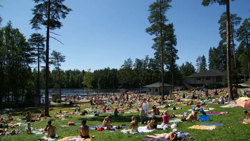 Suomalaiset ottavat aurinkoa Kuusijärvellä Vantaalla kesällä