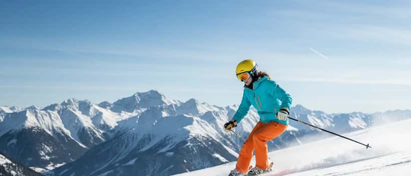Junge Frau in bunter Skiausrüstung beim Skifahren auf einer verschneiten Piste in den deutschen Alpen