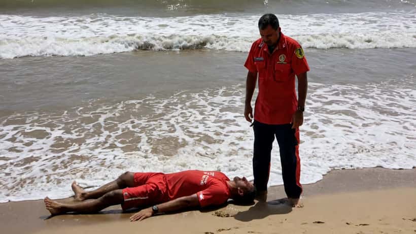 Salva-vidas realizando RCP em vítima de afogamento na praia