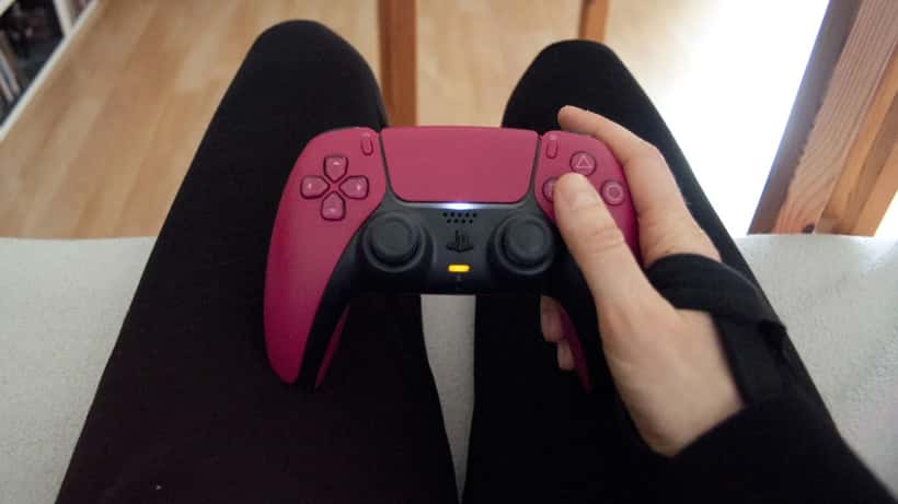 Person holding a PS5 DualSense controller during a gaming session