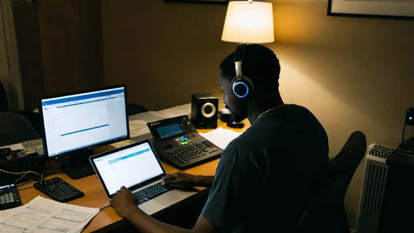 Músico revisando documentos financieros y datos de streaming en su estudio casero