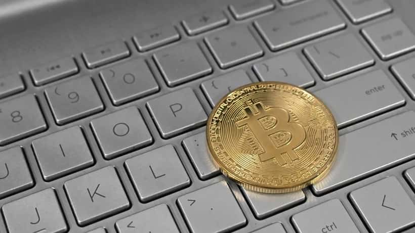 Moneda de Bitcoin sobre un teclado portatil simbolizando la inversion cripto
