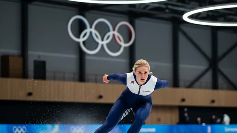 Skridskoåkare på is i olympisk skridskoposition med fart och intensitet
