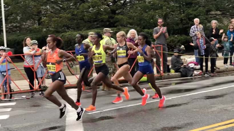 Women runners competing in the Boston Marathon on a city street
