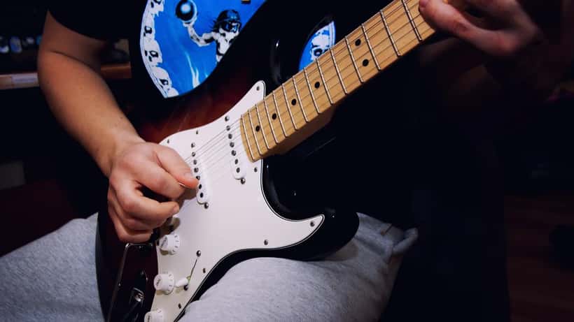 Músico de rock tocando guitarra eléctrica en un concierto con luces de escenario