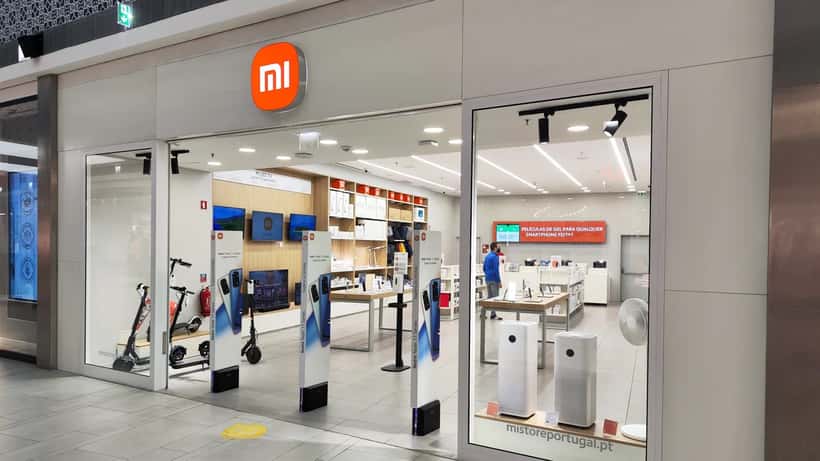 Loja Xiaomi em Portugal com smartphones expostos e ecrãs a mostrar interface HyperOS