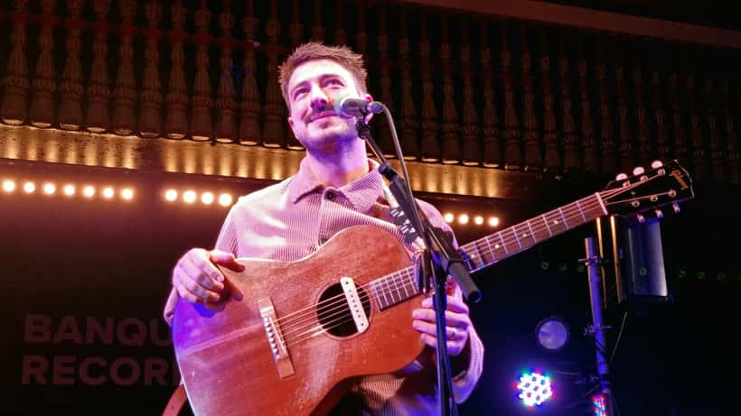 Marcus Mumford performing live at a concert venue