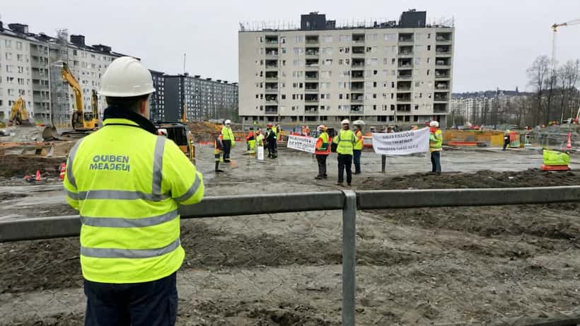 Norske bygningsarbeidere i gule refleksvester samlet utenfor en byggeplass under streik i Oslo 2026