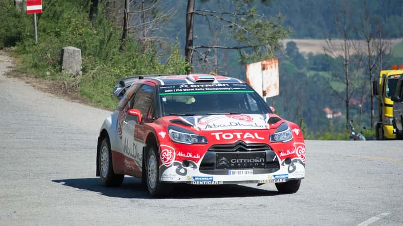 Carro de rali WRC em ação numa especial do Rally de Portugal, com multidão de espetadores em fundo