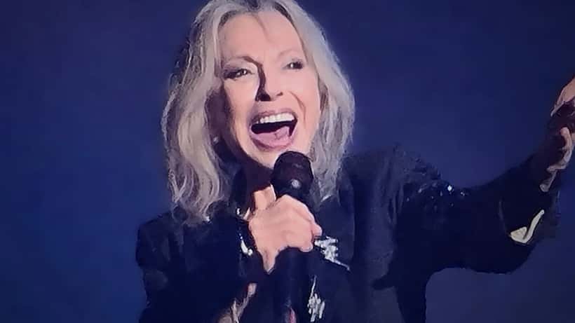 Femme d'âge mûr devant un microphone en coulisses d'une salle de concert