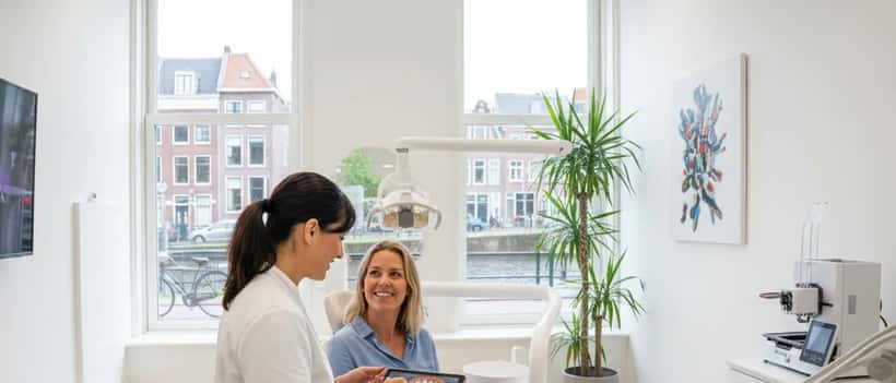 Nederlandse vrouw in tandartsstoel in modern Amsterdams tandartsenpraktijk, consult met tandarts over behandelplan 2026