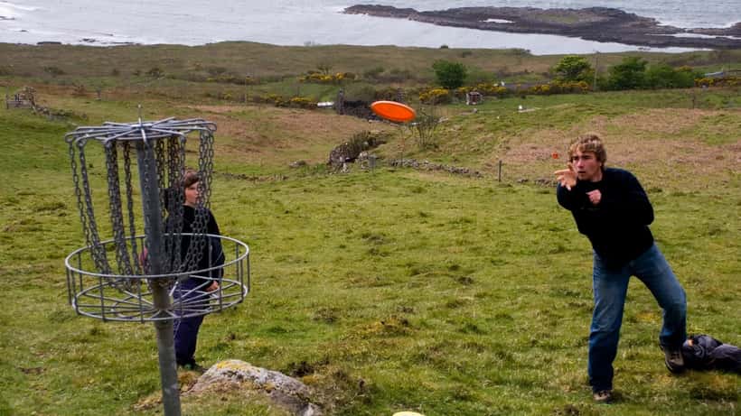 Frisbeegolfaaja heittää kiekon puisessa maisemassa turnauksessa
