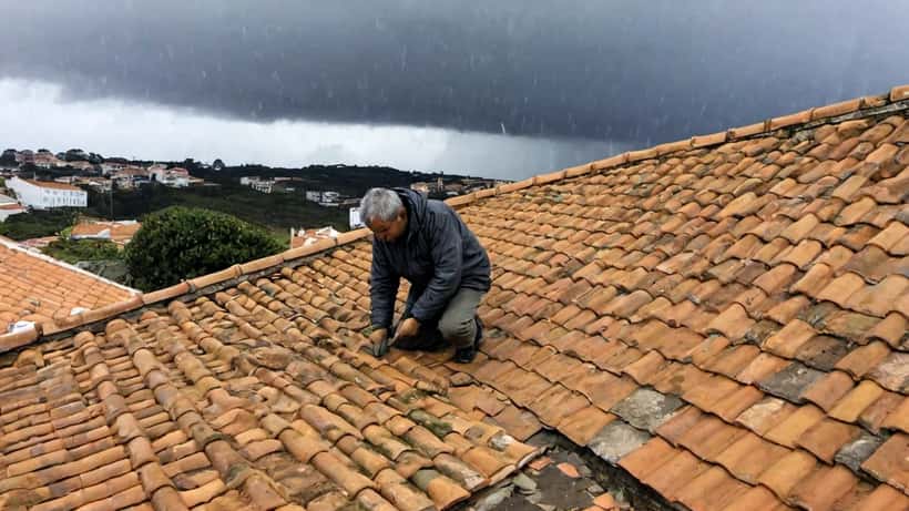 Proprietário a inspecionar danos no telhado após trovoada em Portugal