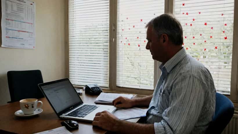 A UK investor looking concerned at a laptop displaying a trading platform with declining charts