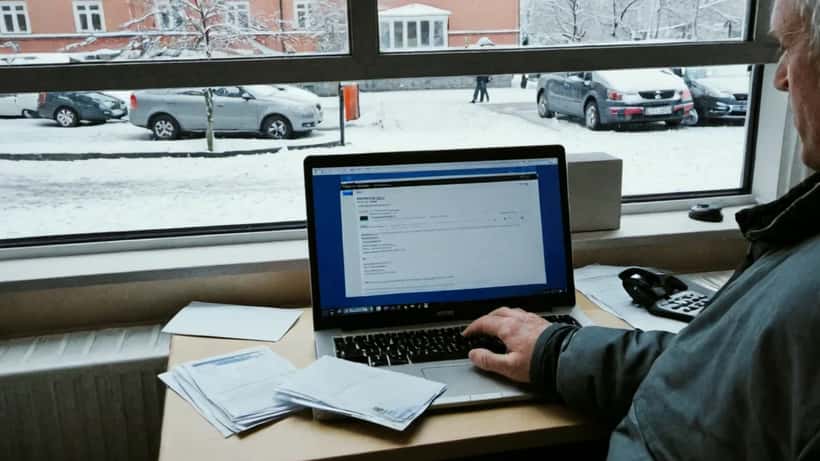 Suomalainen henkilö katsoo Suomi.fi-palvelua kannettavalta tietokoneelta, paperikirjeitä pöydällä vieressä