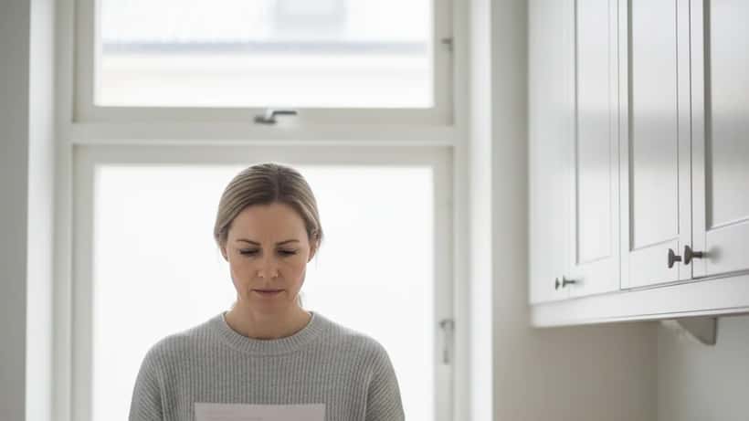 Svensk kvinna läser hyresavi med oro på ansiktet i Göteborg-lägenhet