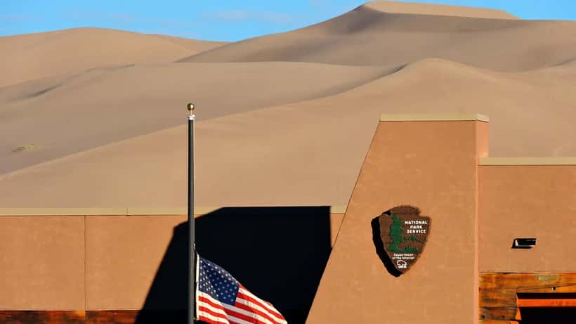 American flag flying at half-staff on a clear day at Great Sand Dunes National Park