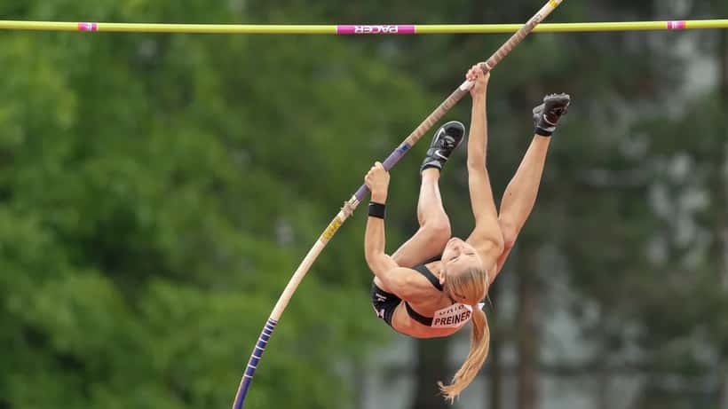 Athlète de saut à la perche en compétition, illustrant les exigences physiques des sports de haut niveau