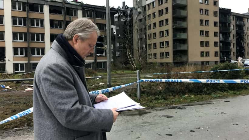 Advokat undersöker skador på fasad utanför byggnad i Göteborg efter explosion