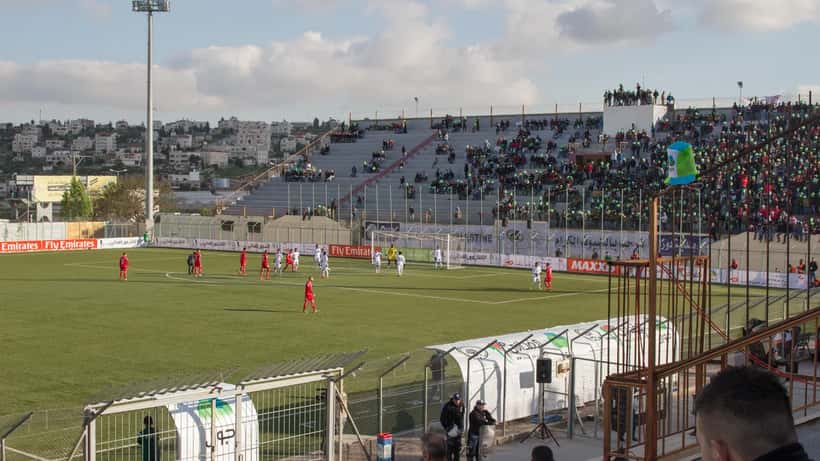 Publik på fullsatt fotbollsstadion under kvällsmatch