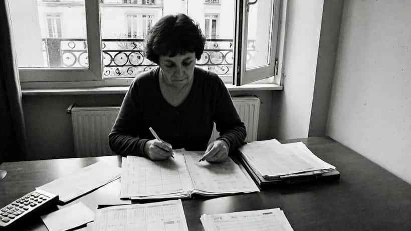Mère de famille consultant ses documents d'allocations CAF à domicile