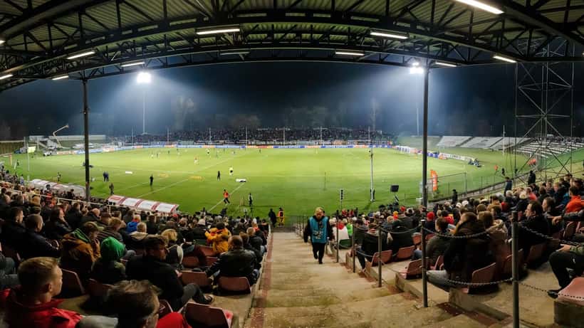 European football stadium at night with floodlights illuminating packed stands